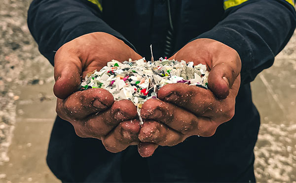 Man holding shreds of plastic in his bare hands.